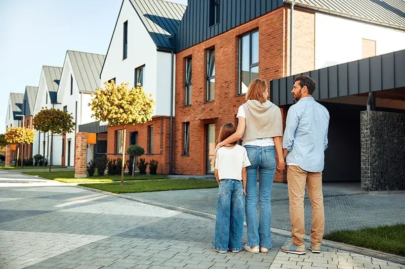 : Family outside new housing estate home with PhoneWatch alarm system installed