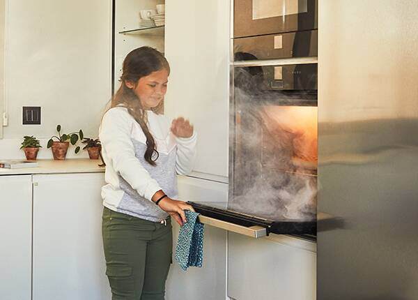 Smoke from an oven filling a kitchen, the type of early fire a PhoneWatch monitored smoke alarm detects