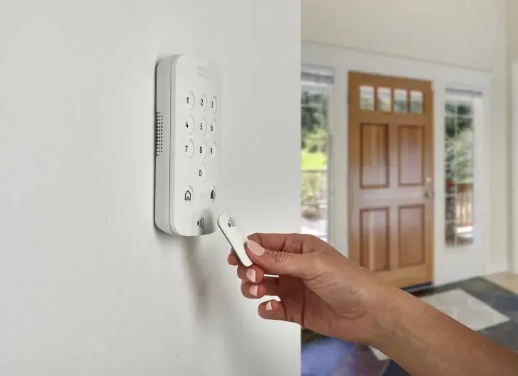 Person testing a PhoneWatch home alarm keypad during routine home alarm maintenance in an Irish hallway