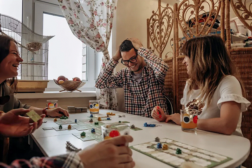 Family and friends gathered around a table playing a board game