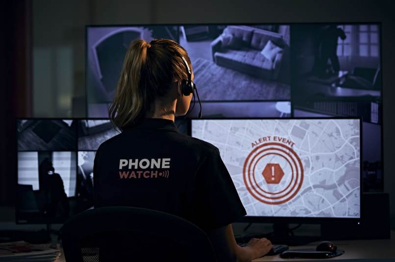 PhoneWatch monitoring operator responding to a security alert across multiple surveillance screens