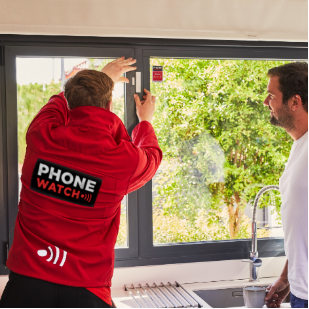 A PhoneWatch security advisor installing a sensor on a window as part of a farm alarm system.