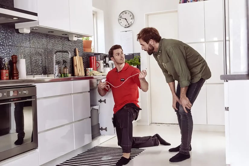 engineer installing water leak detector in kitchen 