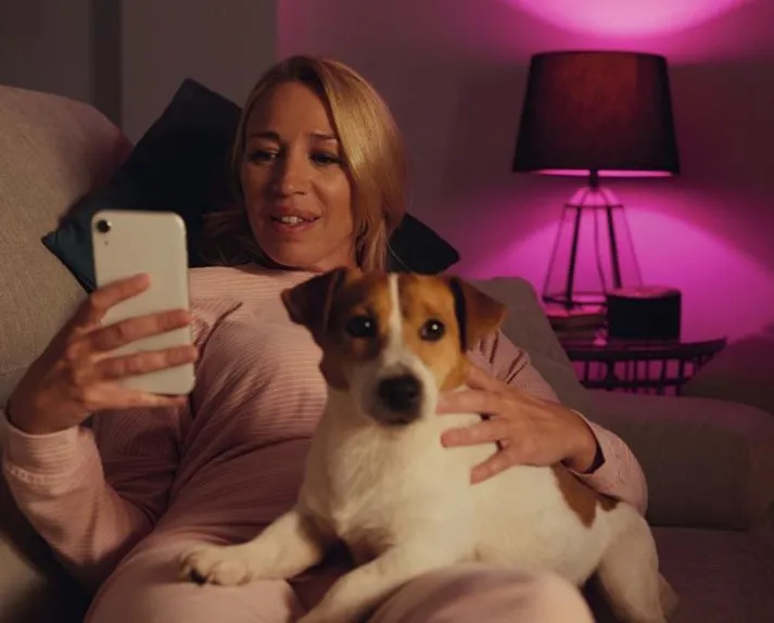 woman looking at phone in smart home. dog sitting on her lap